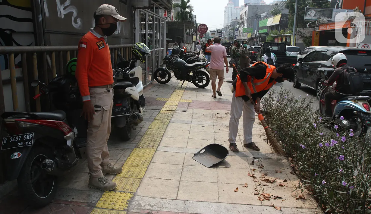 Warga pelanggar PSBB dihukum menyapu saat terjaring razia masker di Jalan Tanjung Duren Raya, Jakarta, Jumat (11/9/2020). Petugas Satpol PP gencar melakukan razia masker menyusul kasus COVID-19 di DKI Jakarta yang terus meningkat. (merdeka.com/Imam Buhori)