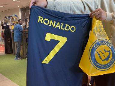 Kepastian bergabungnya Cristiano Ronaldo pada 31 Desember 2022 bersama klub papan atas Arab Saudi, Al Nassr langsung berpengaruh signifikan dari sisi bisnis. Para fans Al Aalami, julukan bagi Al Nassr, berbondong-bondong mengunjungi toko resmi pernak-pernik klub Al Nassr di Riyadh untuk berburu jersey bernomor punggung 7 bertuliskan "Ronaldo". (AFP/Fayez Nureldine)
