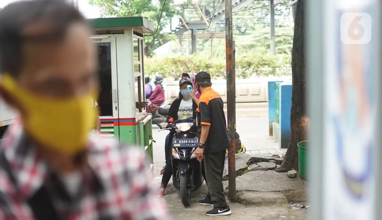 Petugas mengecek suhu tubuh pengunjung yang masuk ke kawasan Pasar Minggu, Jakarta, Selasa (23/6/2020). Pascapenutupan tiga hari terkait ditemukannya tiga pedagang yang positif COVID-19, pengunjung Pasar Minggu kini diwajibkan mencuci tangan dan cek suhu tubuh. (Liputan6.com/Immanuel Antonius)