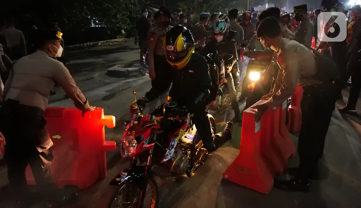 Polisi membuka pembatas jalan saat pemudik motor melintas di posko penyekatan mudik di Kedungwaringin, Kabupaten Bekasi, Jawa Barat, Selasa (11/5/2021) dini hari. Polisi kembali memberlakukan diskresi terhadap pemudik motor karena jumlahnya tidak terbendung. (Liputan6.com/Herman Zakharia)