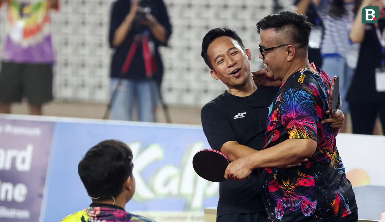 Dua komedian Indonesia, Abdel Achrian (kanan) dan Denny Cagur saat bertanding tenis meja di Turnamen Olahraga Selebriti Indonesia yang berlangsung di GOR Universitas Negeri Jakarta, Sabtu (29/7/2023). (Bola.com/Abdul Aziz)