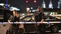 Dua polisi bersenjata memblokade kawasan London Bridge, setelah serangan teror, Sabtu (3/6). Serangan teror terjadi di London Bridge dan Borough Market, yang dilakukan lima orang pria dan menewaskan 6 orang termasuk pelaku. (Dominic Lipinski/PA via AP)