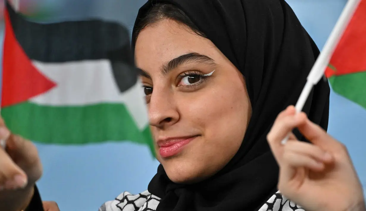 Seorang pendukung mengibarkan bendera sebelum dimulainya pertandingan sepak bola Grup C Piala Asia AFC Qatar 2023 antara Palestina dan Uni Emirat Arab di Stadion Al-Janoub di Al-Wakrah, sebelah selatan Doha pada 18 Januari 2024. (HECTOR RETAMAL/AFP)