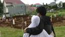Kerabat menyaksikan pemakaman anggota keluarganya yang dimakamkan dengan protokol COVID-19 di area khusus TPU Srengseng Sawah, Jakarta, Kamis (14/1/2021). TPU Srengseng Sawah mulai menerima pemakaman jenazah dengan protokol COVID-19 sejak Selasa (12/1) lalu. (Liputan6.com/Helmi Fithriansyah)