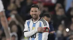 Pemain Timnas Argentina, Lionel Messi, yang baru bermain dari bangku cadangan hanya bisa tersenyum ketika rekan satu timnya Nicolas Otamendi memberikan ban kapten saat pertandingan Kualifikasi Piala Dunia 2026 zona CONMEBOL melawan Paraguay di Stadion Mas Monumental, Jumat (13/10/2023) pagi WIB. (AFP/Juan Mabromata)