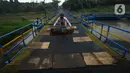 Warga menaruh kain pada jembatan perahu di atas Sungai Citarum, Karawang, Jawa Barat, Sabtu (20/11/2021). Jembatan perahu ini menjadi jalan alternatif yang menghubungkan antara Desa Anggadita dengan Kawasan Pabrik Dusun Rumambe 1. (merdeka.com/Imam Buhori)