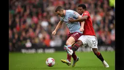 Pemain MU, Tyrell Malacia (kanan) berusaha merebut bola dari kaki pemain Aston Villa, John McGinn, dalam pertandingan pekan ke-34 Liga Inggris 2022/2023 yang berlangsung di Old Trafford, Minggu (30/4/2023). (AFP/Oli Scarff)