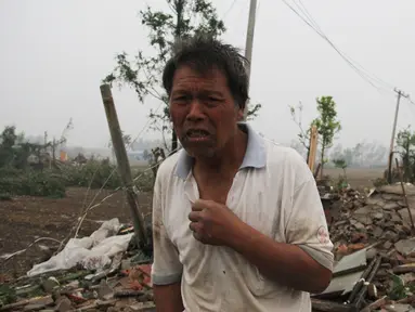 Seorang pria berdiri di depan puing bangunan rumahnya akibat tornado menyapu wilayah Yancheng, Provinsi Jiangsu, Tiongkok, Kamis (23/6). Cuaca ekstrim termasuk hujan es, hujan lebat, dan angin puting beliung itu menewaskan sedikitnya 51 orang. (STR/AFP)