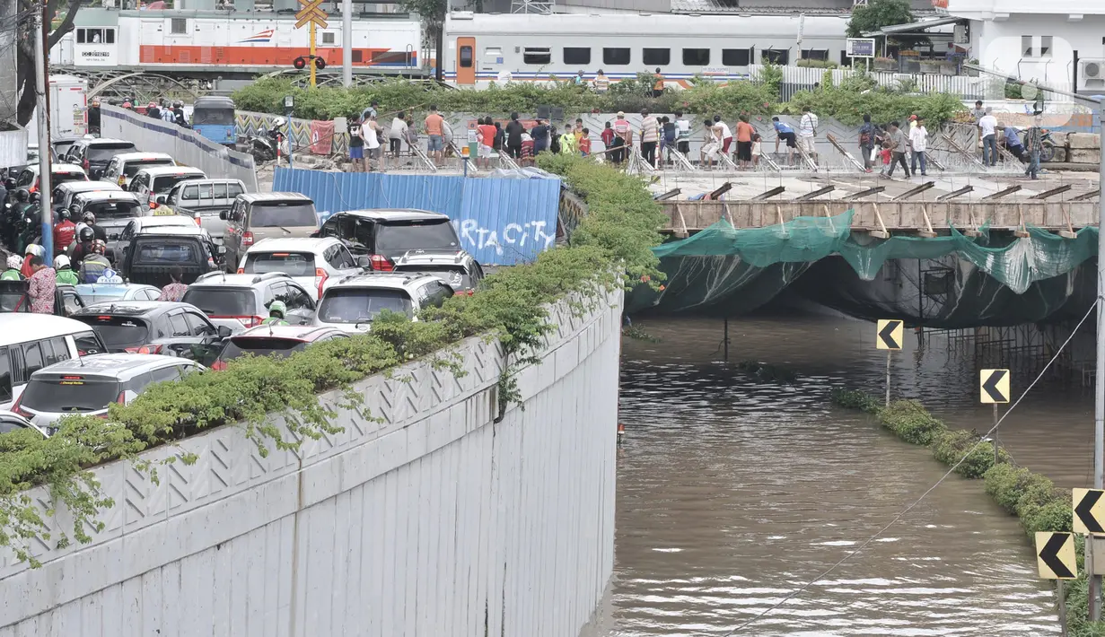 Warga melihat banjir yang merendam Underpass Senen, Jakarta, Selasa (25/2/2020). Hujan deras yang mengguyur Ibu Kota sejak dini hari tadi menyebabkan Underpass Senen terendam banjir setinggi dua meter sehingga mengakibatkan akses Cempaka Putih-Pasar Senen terputus. (merdeka.com/Iqbal Nugroho)
