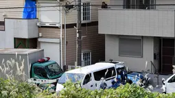 Seorang pria berada di samping rumah yang ditutupi kain biru di mana polisi menemukan sembilan mayat termasuk dua kepala yang disimpan di kotak pendingin di Zama, Prefektur Kanagawa, Jepang, (31/10). (AFP Photo/Toru Yamanaka)