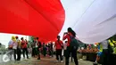 Seorang peserta 'Aksi Kita Indonesia' berfoto dibawah Bendera Merah Putih di Bundaran HI, Jakarta, Minggu (4/12). Ada banyak bendera Merah Putih dikibarkan oleh para peserta aksi hingga membuat Bundaran HI tampak memerah. (Liputan6.com/Angga Yuniar)