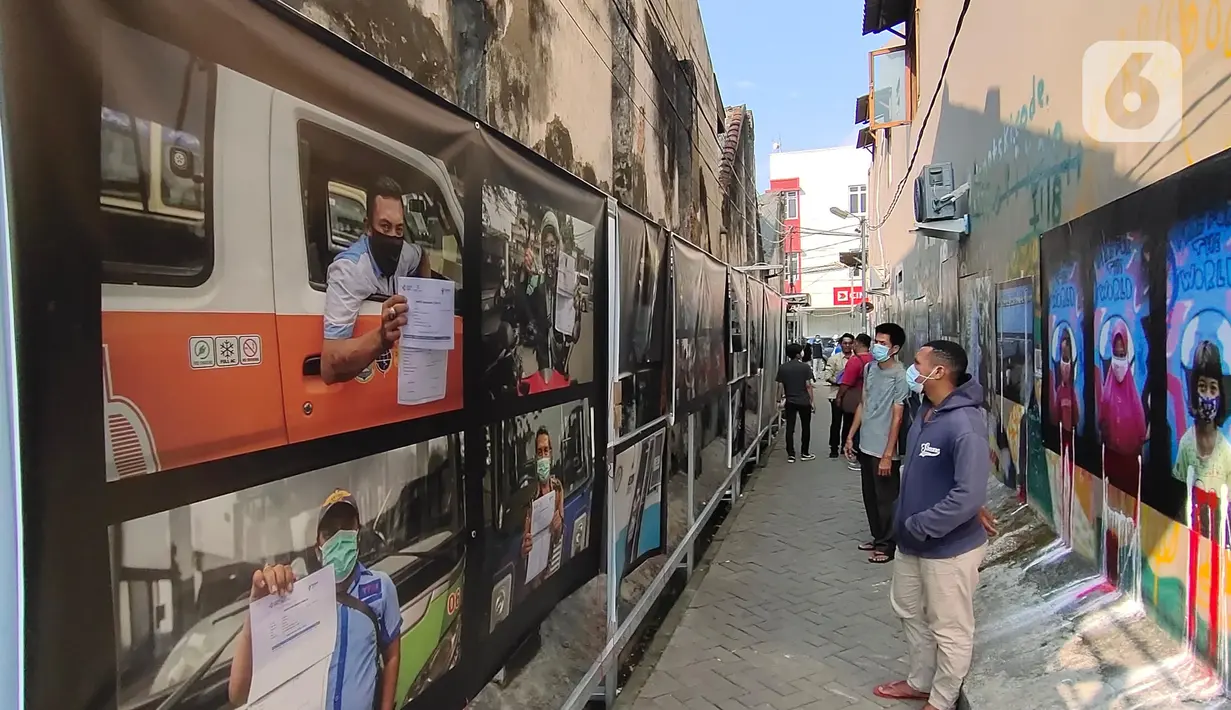 Warga melihat pameran foto jurnalistik karya pewarta foto Indonesia Tangerang di kawasan Pasar Lama, Tangerang, Minggu (30/5/2021). Pameran foto ini juga mengingatkan masyarakat terus menjaga protokol kesehatan untuk indonesia yang sehat. (Liputan6.com/Angga Yuniar)