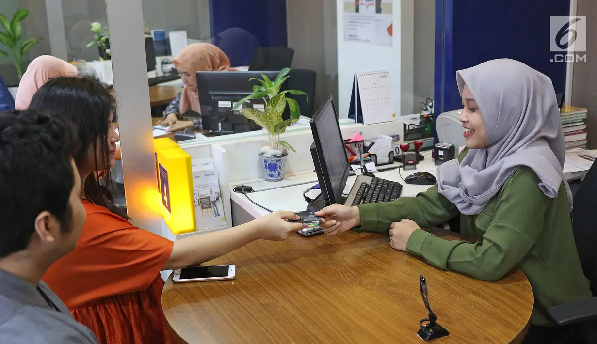 Nasabah memberikan kartu ATM ke petugas saat melakukan pengaduan di Bank Mandiri KCP Jakarta Mal Pondok indah 2, Sabtu (20/7/2019). Nasabah Bank Mandiri mengeluhkan perubahan drastis saldo di rekening yang mengalami pengurangan dan ada juga yang mengalami penambahan. (Liputan6.com/Herman Zakharia)
