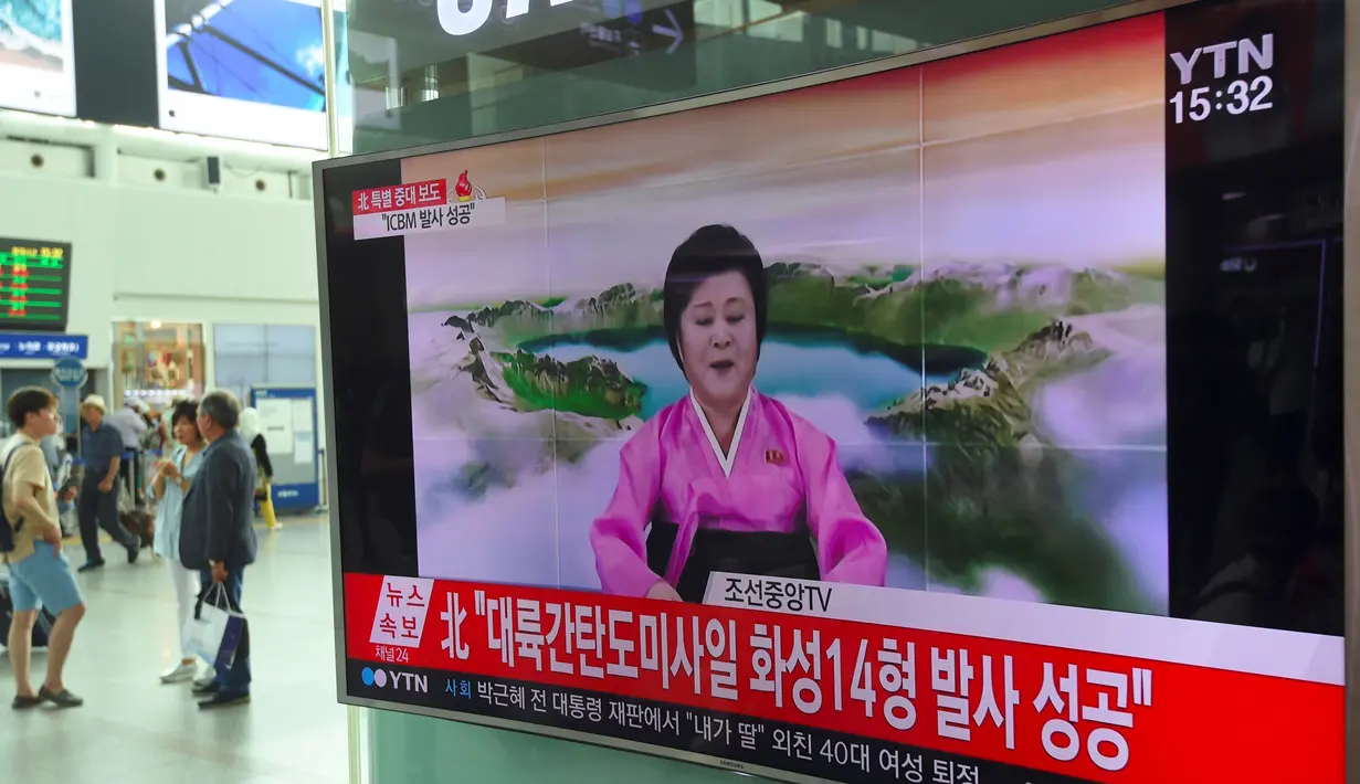 Warga menonton penyiar berita Korea Utara, Ri Chun-Hee menginformasikan berita tentang tes ICBM baru di stasiun kereta di Seoul pada 4 Juli 2017. Saat itu Korut memproklamirkanelah berhasil menguji rudal balistik antar benua. (AFP Photo/Jung Yeon-Je)