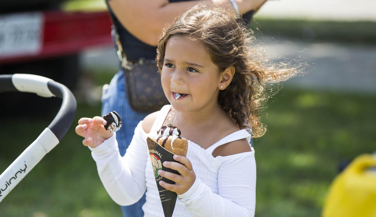 Seorang anak perempuan menikmati es krimnya saat Festival Es Krim Toronto di Toronto, Kanada, Sabtu (15/8/2020). Festival Es Krim Toronto diadakan pada 15-16 Agustus 2020 di tengah pandemi COVID-19. (Xinhua/Zou Zheng)