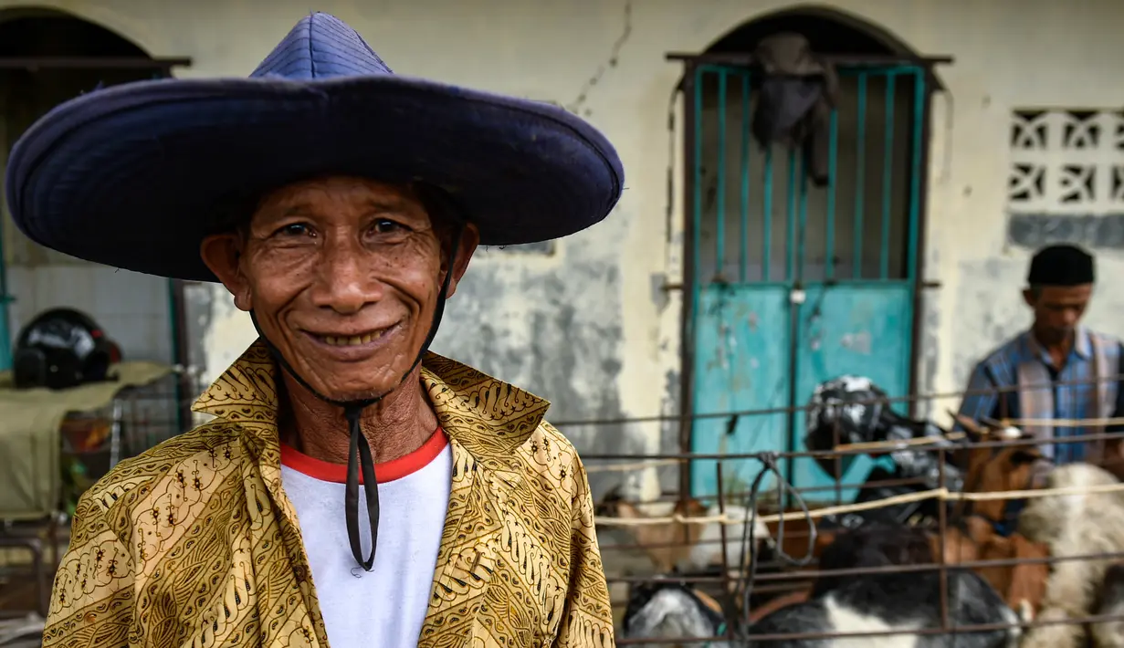 Seorang pria tersenyum di pasar yang menjual ternak menjelang perayaan Idul Fitri yang menandai akhir bulan suci Ramadan di Sibreh, provinsi Aceh (20/5/2020). (AFP/Chaideer Mahyuddin)