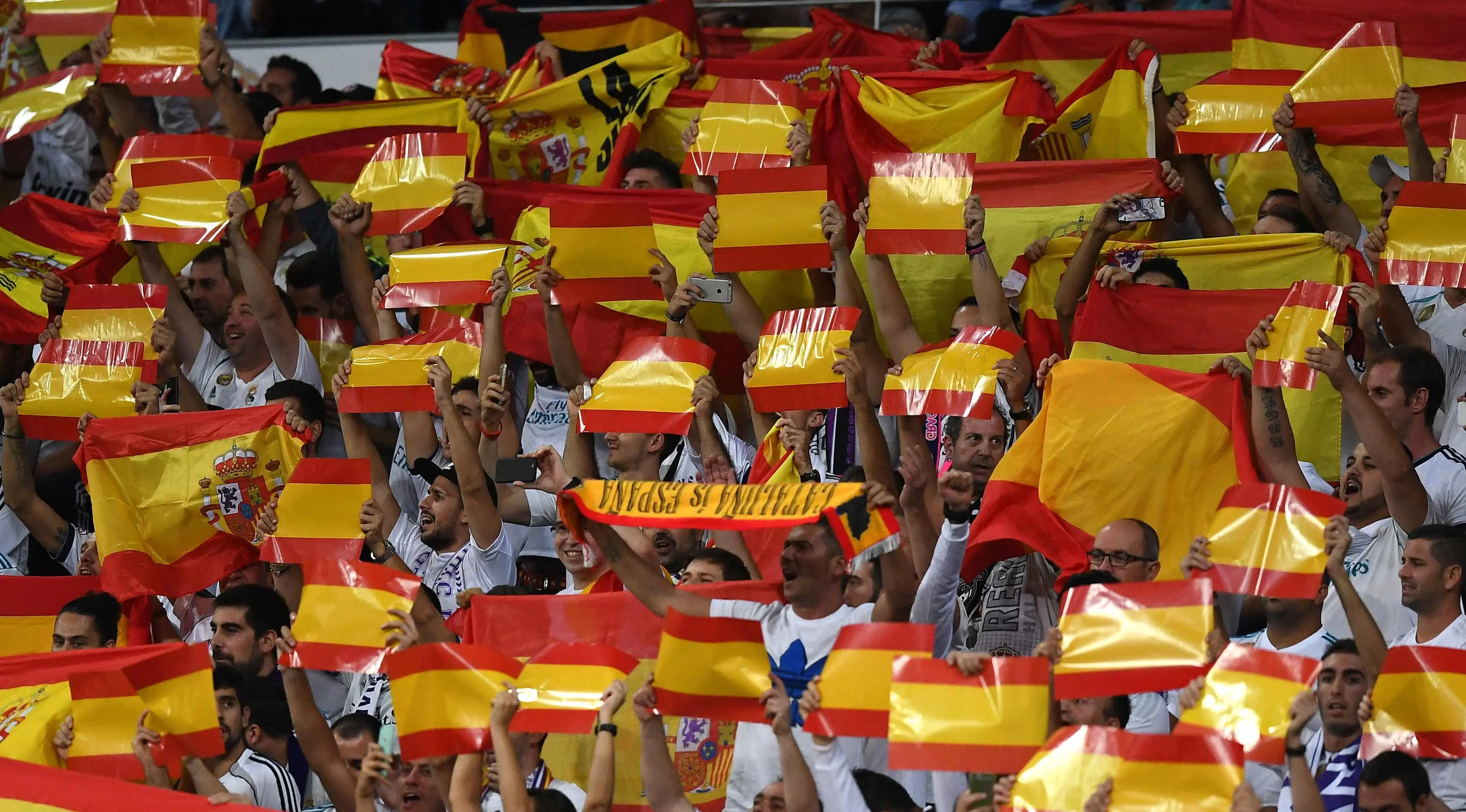 Suporter Real Madrid membentangkan bendera Spanyol saat pertandingan melawan Espanyol di Santiago Bernabeu, Spanyol (1/10). Warga Catalonia mengikuti referendum Minggu (1/10) untuk memutuskan memerdekakan diri atau tidak. (AFP Photo/Gabriel Bouys)