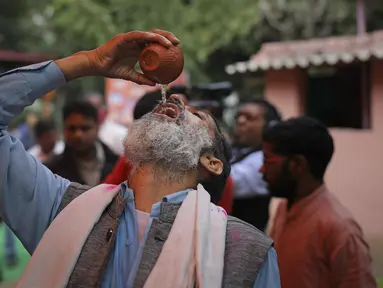 Seorang pria Hindu India minum urin sapi selama acara kelompok agama Hindu untuk mempromosikan konsumsi urin sapi sebagai obat virus corona Covid-19 di New Delhi, India, Sabtu, (14/3/2020). Sekitar 200 orang menghadiri acara minum urin sapi tersebut. (AP Photo/Altaf Qadri)