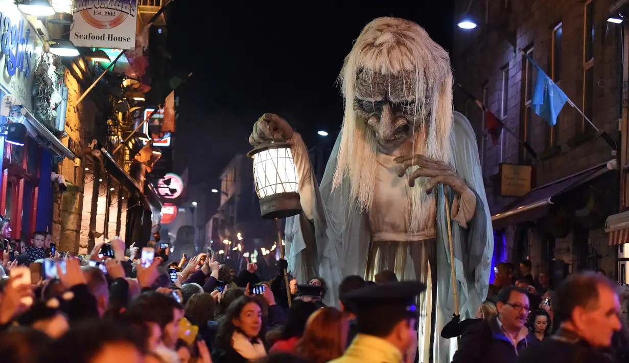 Sejumlah warga melihat nenek sihir raksasa saat menghadiri Parade Halloween di Irlandia (30/10). Parade ini untuk merayakan hari Halloween yang jatuh pada tanggal 31 Oktober. (REUTERS/Lucy Nicholson)