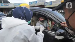 Petugas memeriksa surat keterangan lolos uji rapid test pada warga yang akan melakukan perjalanan di Pos Pam Puncak Pass, Jawa Barat, Minggu (17/5/2020). Ratusan kendaraan dipulangkan ke daerah asalnya dari wilayah Bogor Depok dan Jakarta karena melanggar PSBB parsial.  (merdeka.com/Arie Basuki)