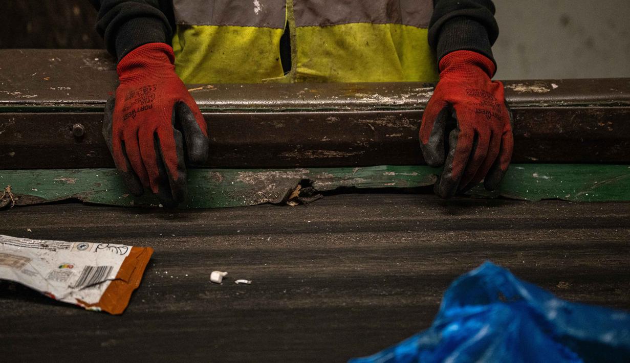Program ini bertujuan mengatasi masalah sampah di pulau tersebut. Tampak dalam foto, seorang pekerja memisahkan benda-benda plastik dari bahan limbah lainnya di atas conveyor belt di pabrik daur ulang di kota Corfu pada 15 Oktober 2025. (Angelos TZORTZINIS/AFP)