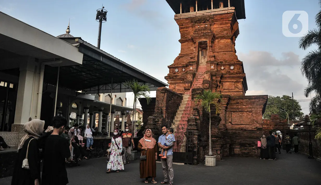 Peziarah berfoto dengan latar Menara Kudus, Kauman, Kabupaten Kudus, Jawa Tengah, Rabu (30/3/2022). Menara berusia 473 tahun yang dahulu berfungsi sebagai tempat mengumandangkan azan menjadi lokasi favorit pengunjung untuk bersantai usai berziarah di Makam Sunan Kudus. (merdeka.com/Iqbal S. Nugroho)