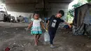 Anak-anak membawa air minum setelah mengisi dari keran kota di bawah jembatan di daerah kumuh di Kalkuta, India (26/5/2016). Kalkuta didirikan Inggris pada 1690 merupakan pusat industri goni dan tekstil. (REUTERS/Rupak De Chowdhuri)