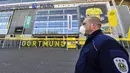 Petugas Keamanan dengan menggunakan masker berjaga di depan Stadion Signal Iduna Park, Jerman, Sabtu (4/4/2020). Stadion Borussia Dortmund ini dialihfungsikan menjadi tempat pusat pengujian COVID-19. (AP/Martin Meissner)