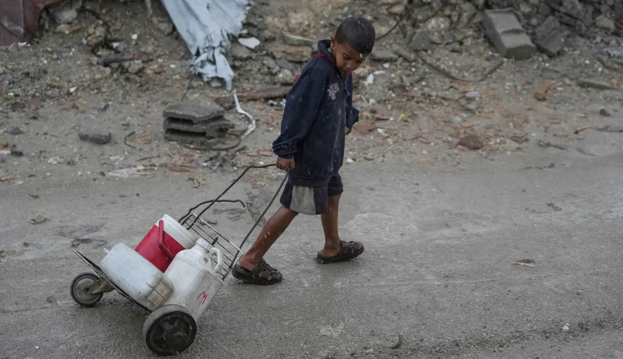Kekurangan air bersih memiliki konsekuensi yang sangat fatal bagi anak-anak di Gaza, di antaranya dehidrasi dan malnutrisi, munculnya beragam penyakit, hingga kehilangan nyawa. Tampak dalam foto, seorang anak laki-laki menarik gerobak buatan sendiri yang diisi dengan jerigen plastik berisi air di kawasan Sheikh Radwan, Kota Gaza, pada Jumat 14 November 2025. (AP Photo/Jehad Alshrafi)
