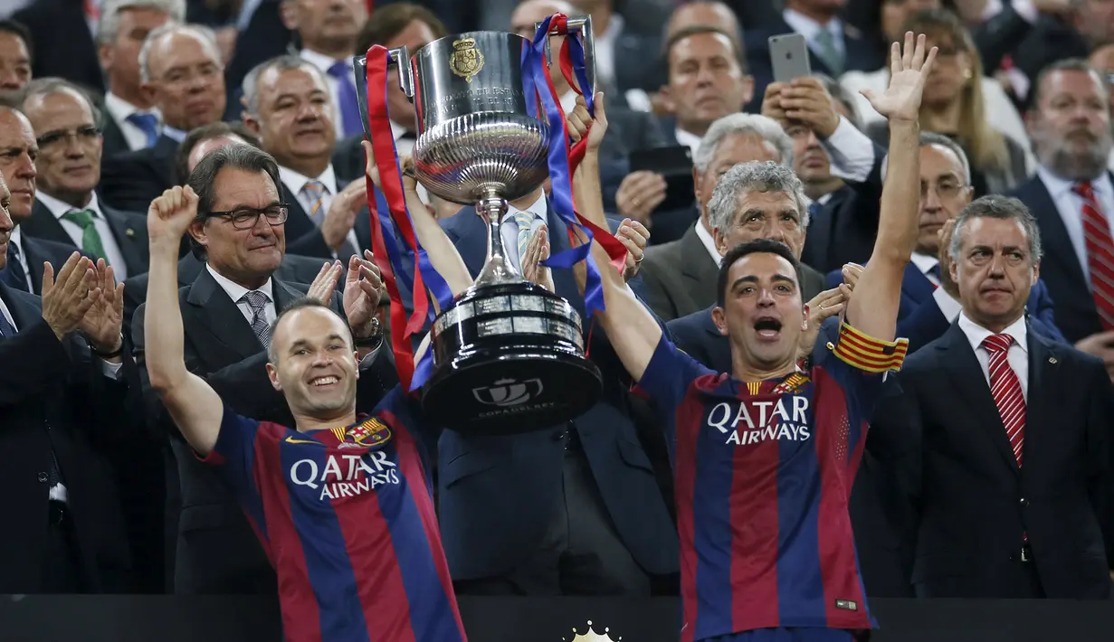 Gelandang Barcelona, Xavi Hernandes (kiri) dan Andres Iniesta mengangkat trofi Copa del Rey usai memenangkan Final Piala Raja di Nou Camp, Spanyol (31/5/2015). Barcelona berhasil menaklukkan Bilbao dengan skor akhir 3-1. (Reuters/Albert Gea)
