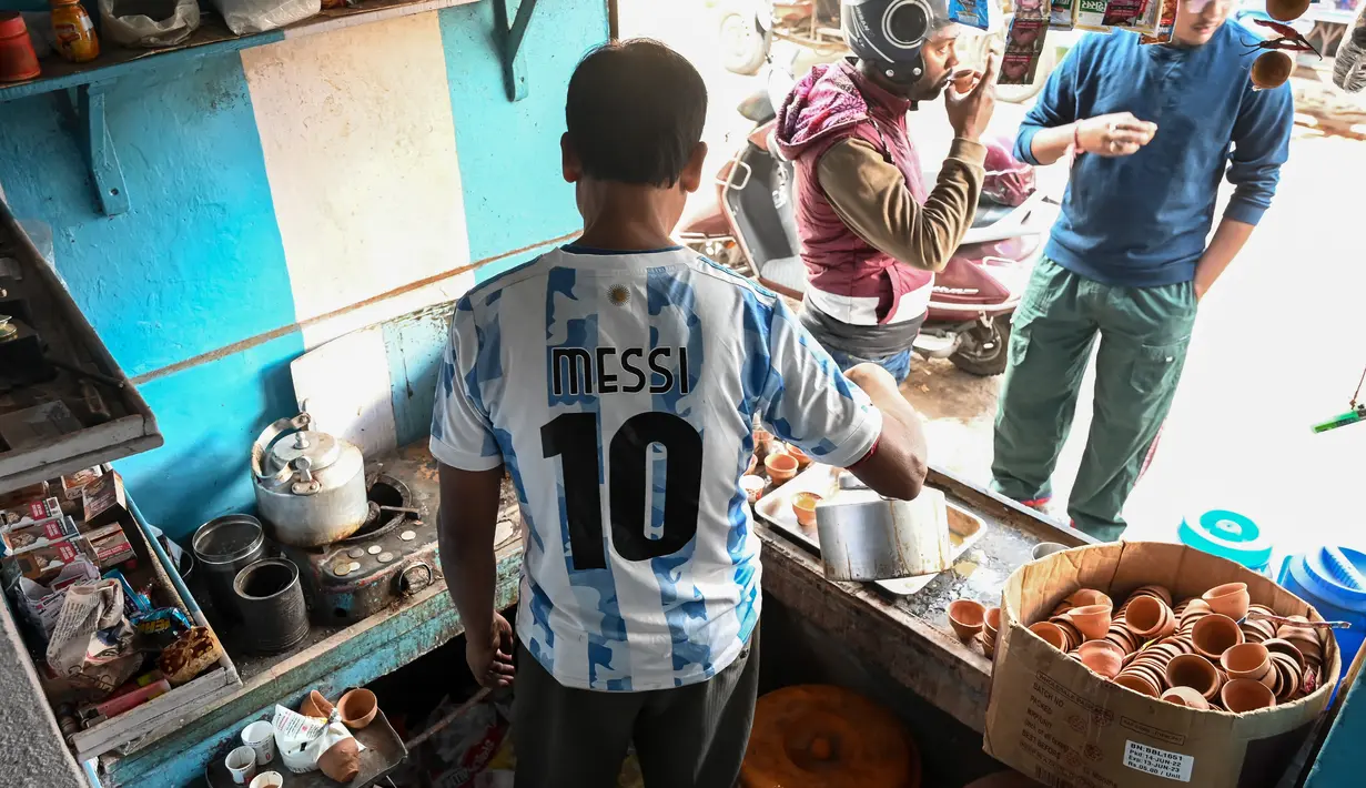 Pemilik warung teh, Shib Shankar Patra sebagai fans timnas Argentina mengenakan jersey saat bekerja di dalam warung tehnya yang dicat dengan warna tim di Ichhapur sekitar 35 km sebelah utara Kolkata pada 12 Desember 2022. Argentina berhasil lolos ke babak semifinal Piala Dunia 2022 Qatar yang akan melawan Kroasia. (AFP/Dibyangshu Sarkar)