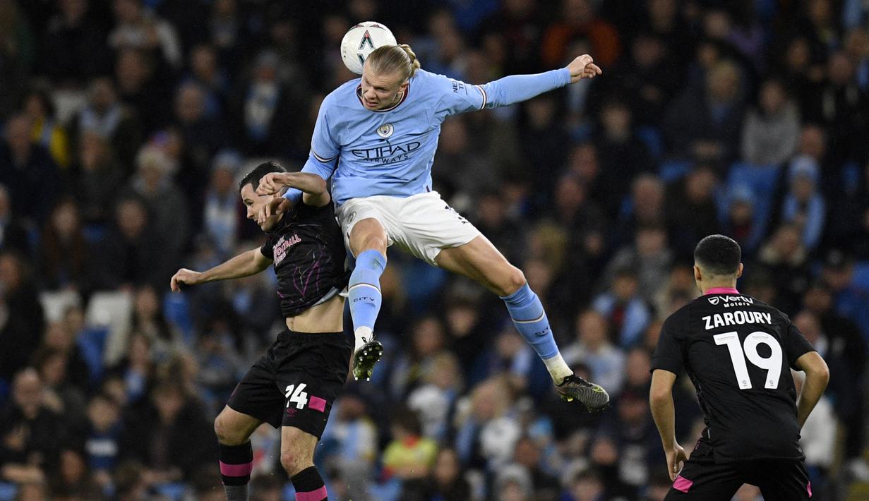 Pemain Manchester City, Erling Haaland (tengah) berebut bola dengan pemain Burnley, Josh Cullen pada laga perempat final FA Cup 2022/2023 yang berlangsung di Etihad Stadium, Manchester, Minggu (19/03/2023) WIB. Haaland sukses mencetak hattrick untuk kemenangan 6-0 The Cityzens. (AFP/Oli Scarff)