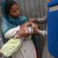 Seorang petugas kesehatan memberikan tetes vaksin polio kepada seorang anak saat kampanye vaksinasi polio dari rumah ke rumah di sebuah kawasan kumuh di Lahore, Paksistan, Senin (23/5/2022). Pakistan meluncurkan upaya anti-polio baru pada hari Senin, lebih dari seminggu setelah pejabat mendeteksi kasus ketiga tahun ini di wilayah barat laut negara itu yang berbatasan dengan Afghanistan. (Arif ALI / AFP)