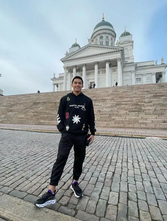 <p>Berpose saat sedang berlibur, Jonatan Christie tampil tidak mengenakan seragam bulu tangkis seperti saat ia sedang di lapangan. Mengenakan hoodie hitam dengan tulisan dan motif, ia padukan penampilannya dengan jogger pants yang juga berwarna hitam, sneakers hitam, dan membawa backpack. Foto: Instagram.</p>