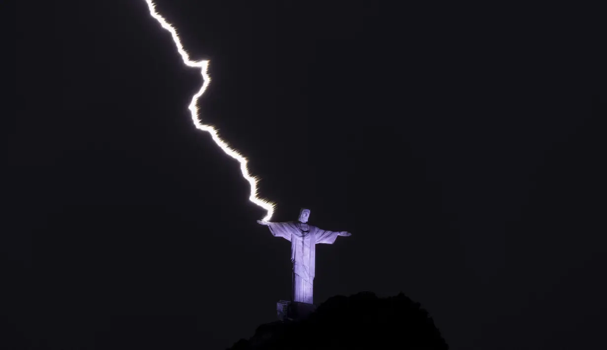 Petir menyambar tangan Christ the Redeemer atau Patung Kristus Penebus di gunung Corcovado di Rio de Janeiro, Brasil, Selasa (21/2/2023). Meskipun ini mungkin bukan pertama kalinya patung itu disambar petir, itu tidak menghilangkan pemandangan luhur dari Ibu Pertiwi yang melakukan kontak dengannya. (Photo by MAURO PIMENTEL / AFP)