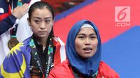 Atlet Taekwondo putri Indonesia, Defia Rosmaniar saat di podium kemenangan Final Women Individual Poomsae di JCC, Jakarta, Minggu (19/8). Defia Rosmaniar meraih emas usai menumbangkan Salahshouri Marjan dari Iran. (Liputan6.com/Helmi Fithriansyah)
