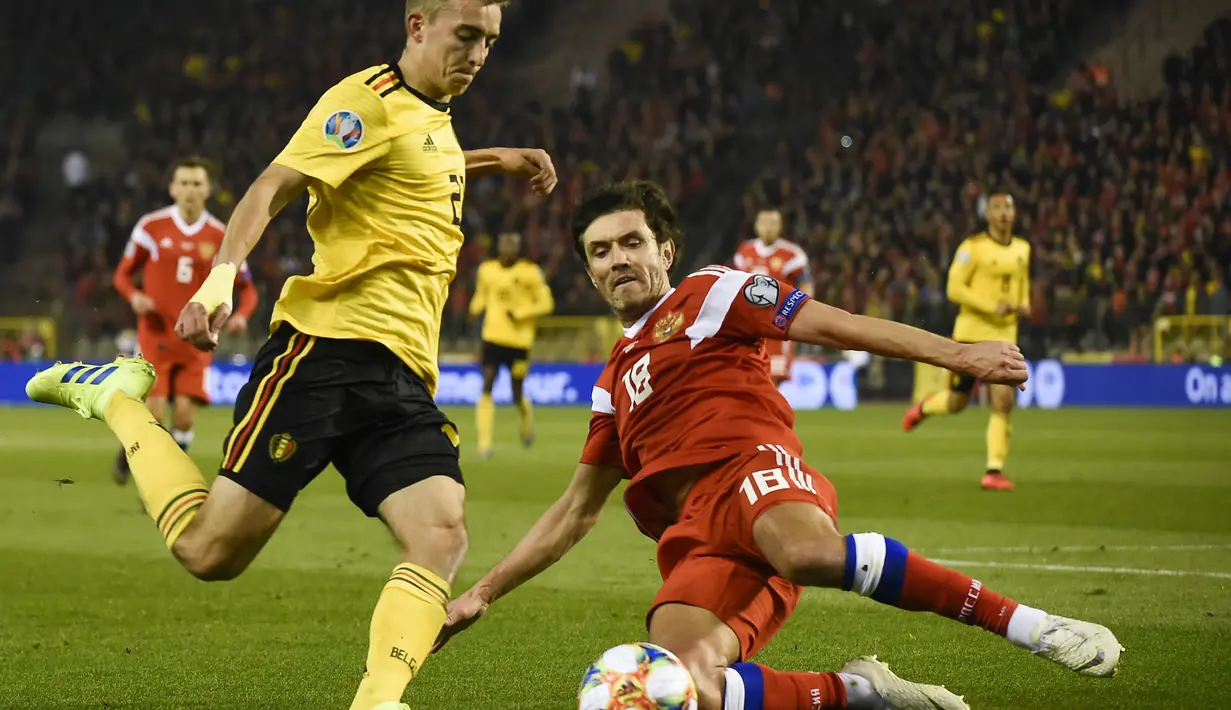Gelandang Belgia, Timothy Castagne mencoba melewati pemain Rusia, Yuri Zhirkov pada laga perdana Kualifikasi Piala Eropa 2020 Grup I yang berlangsung di Stadion Roi Baudouin, Brussels, Jumat (22/3). Belgia menang 3-1 atas Rusia. (AFP/John Thys)
