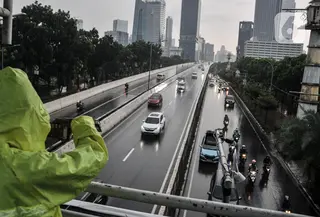 Warga mengenakan jas hujan saat melintasi JPO di Jalan Raya Casablanca, Jakarta Selatan, Selasa (8/3/2022). BMKG memprediksi cuaca ekstrem berupa hujan lebat disertai angin kencang akan terjadi hingga April ini di wilayah Jabodetabek. (merdeka.com/Iqbal S. Nugroho)