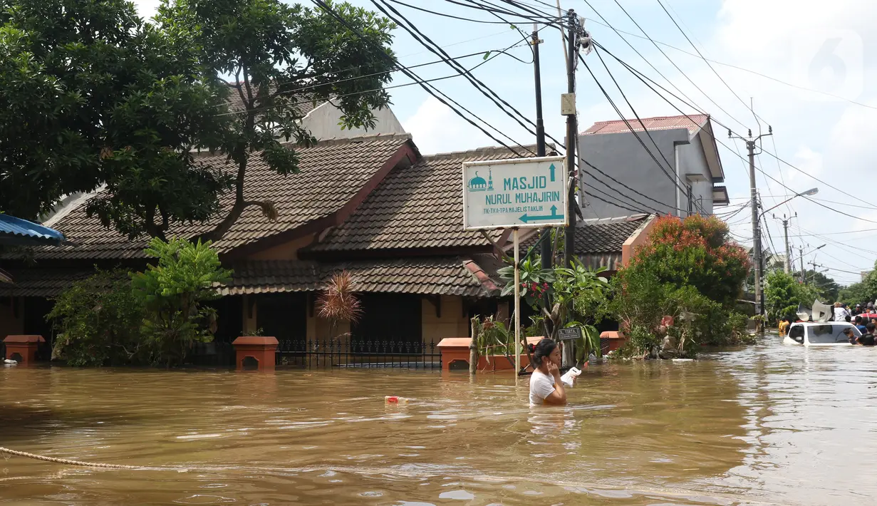 Warga melintasi banjir yang merendam perumahan Ciledug Indah, Tangerang, Banten, Kamis (2/1/2020). Memasuki hari kedua, kondisi perumahan tersebut masih tergenang banjir setinggi dada orang dewasa. (Liputan6.com/Angga Yuniar)