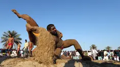 Seorang pegulat Pakistan membanting lawannya saat bertarung dalam kompetisi gulat Greco-Roman mingguan di Dubai (16/3). Mereka melakukan pertandingan gulat gaya kuno. (AFP Photo/Karim Sahib)