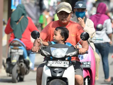 Pengendara motor tidak mengenakan masker masuk ke Pasar Bukit di Tangerang Selatan, Banten, Rabu (22/7/2020). Warga masih tidak peduli kesehatan dirinya sendiri dan orang lain, tentang bahayanya penyeberan virus corona (COVID-19) yang terus meningkat di Indonesia. (merdeka.com/Dwi Narwoko)