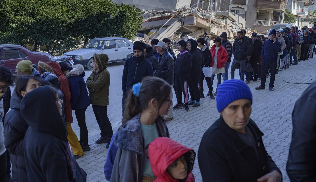 Warga mengantri di luar toko roti yang membagikan roti gratis di Samandag, selatan Hatay pada 16 Februari 2023, sepuluh hari setelah gempa berkekuatan 7,8 melanda wilayah perbatasan Turki dan Suriah. Perserikatan Bangsa-Bangsa (PBB) meminta dana bantuan sebesar USD1 miliar atau Rp15,1 trilun untuk membantu para korban bencana gempa bumi di Turki yang menewaskan ribuan orang dan membuat jutaan lainnya sangat membutuhkan bantuan. (Photo by Yasin AKGUL / AFP)