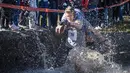Koley True dan Thomas Trundy melewati kolam lumpur selama North American Wife Carrying Championship di Sunday River Resort di Newry, Maine, pada 8 Oktober 2022. Siapa yang mencapai garis finis dengan catatan waktu paling cepat sembari menggendong istri, dialah yang menang. (Joseph Prezioso / AFP)