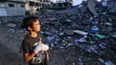 Seorang anak laki-laki Palestina yang terluka, Mohammed Sofi, 12 tahun, melihat bangunan yang hancur akibat serangan udara Israel di dekat rumahnya di kamp pengungsi Rafah, selatan Jalur Gaza, pada 16 Oktober 2023. (MOHAMMED ABED/AFP)
