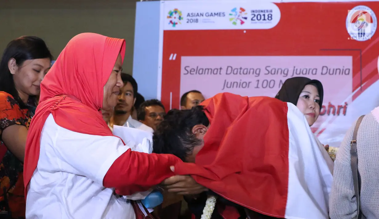 Pelari muda Indonesia, Lalu Muhammad Zohri (kanan) mencium tangan kakak tertuanya saat penyambutan di Terminal 3 Bandara Soetta, Tangerang, Selasa (17/7). Lalu M Zohri meraih emas lari 100m putra U-20 IAAF. (Liputan6.com/Helmi Fithriansyah)
