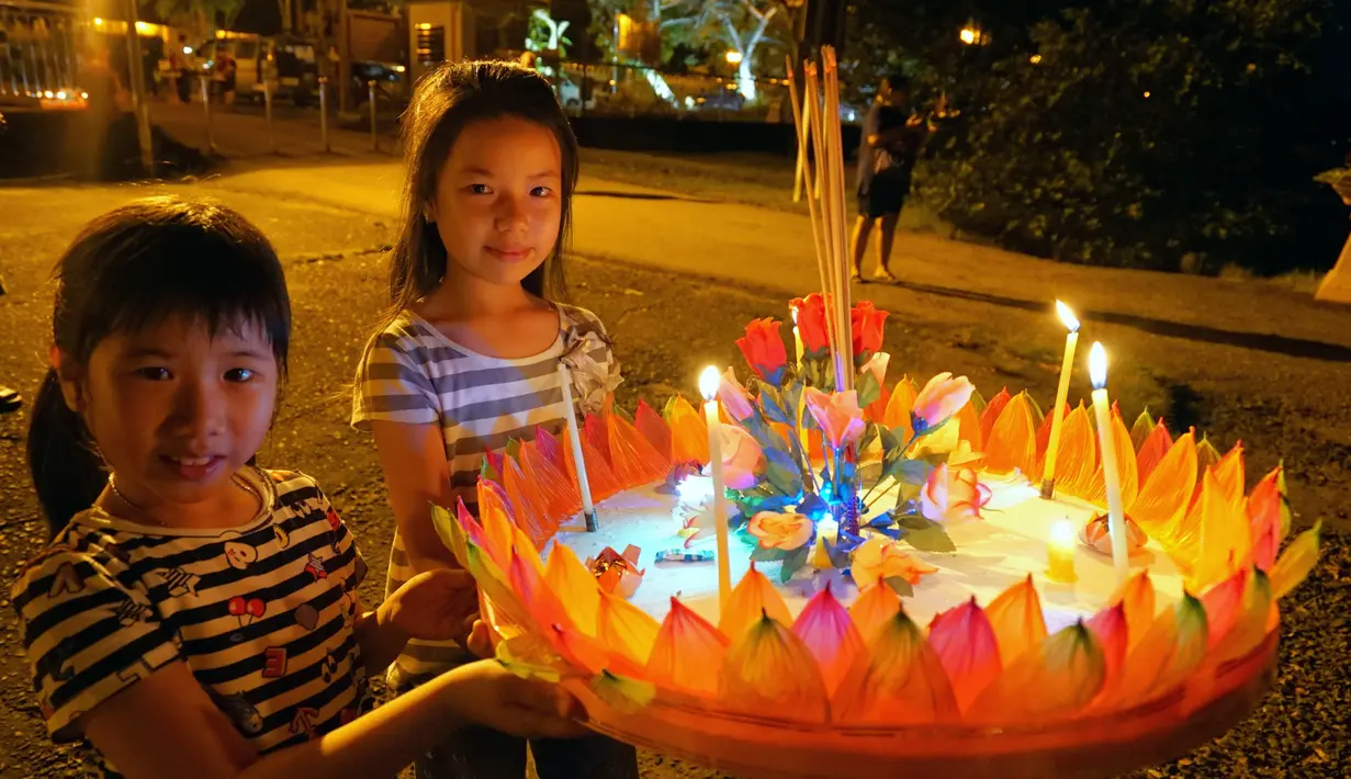 Anak-anak membawa sebuah lentera air untuk dihanyutkan dalam Festival Loy Krathong di Bandar Seri Begawan, Brunei (31/10/2020).  Sekitar 250 orang termasuk sejumlah warga Thailand yang tinggal di Brunei menghanyutkan lentera air untuk perdamaian dan keberuntungan. (Xinhua/Jeffrey Wong)