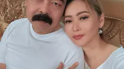 Dalam foto, Inul Daratista dan Adam Suseno kompak pakai atasan putih polos tanpa lengan. Bintang sinetron Kenapa Harus Inul? merengkuh lengan suami. “Lihatlah kita berdua. Coba lihat Mas Adam, dulu cakep sekali. Sekarang matanya juga sudah mulai turun, rambutnya sudah makin botak kalau dihitung tinggal 10 helai sendiri2 pula,” ujarnya. (Foto: Dok. Instagram @inul.d)