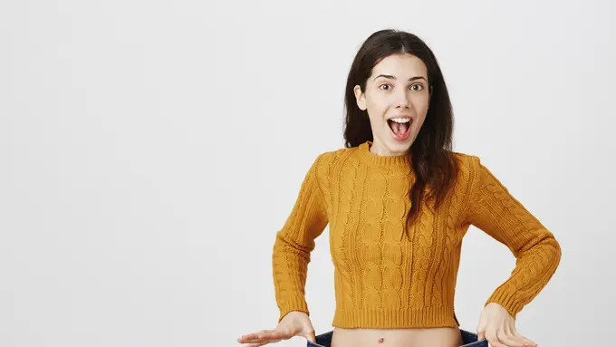 Seorang perempuan memegang jeans dengan ukuran besar (Foto Dok: Freepik/cookie_studio)