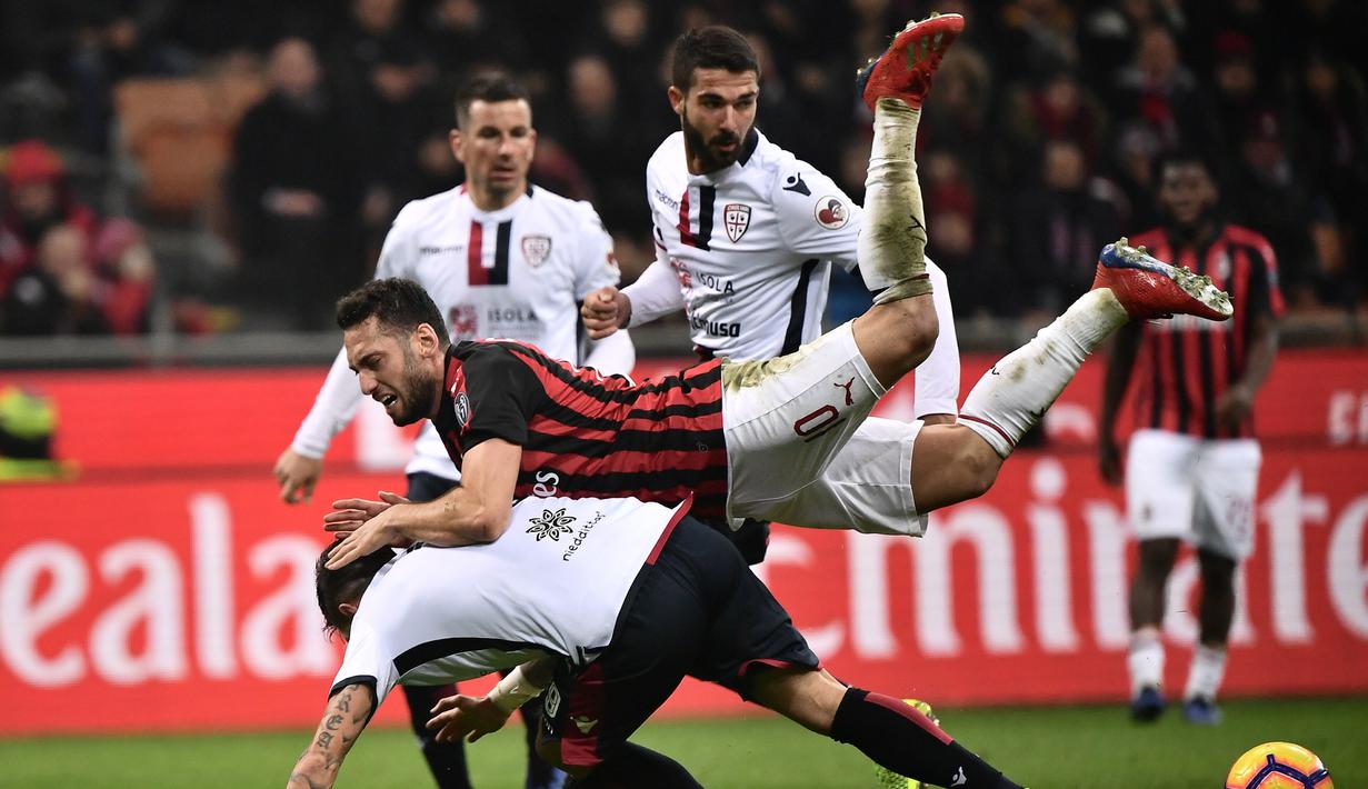 Gelandang AC Milan, Hakan Calhanoglu dijegal oleh pemain Cagliari pada laga lanjutan Serie A yang berlangsung di stadion San Siro, Milan, Senin (11/2). AC Milan menang 3-0 atas Cagliari. (AFP/Marco Bertorello)