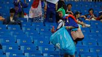 Seorang suporter timnas Jepang mengumpulkan sampah setelah laga 16 besar Piala Dunia 2018 melawan Begia di Rostov Arena, Senin (2/7). Meski timnya tersingkir secara dramatis, tak menghalangi para suporter Jepang melakukan aksi positif. (AP/Pavel Golovkin)